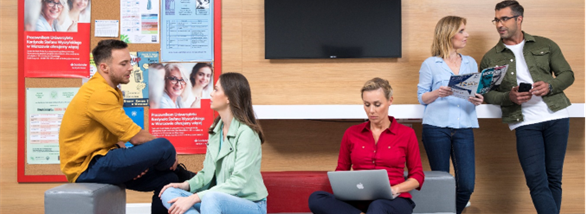 Grupa młodych ludzi z laptopami na kolanach