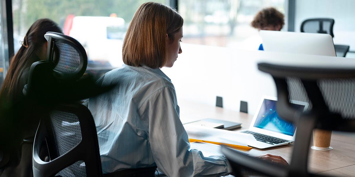 zdjęcie przedstawia kobietę siedzącą przy biurku na ergonomicznym krześle