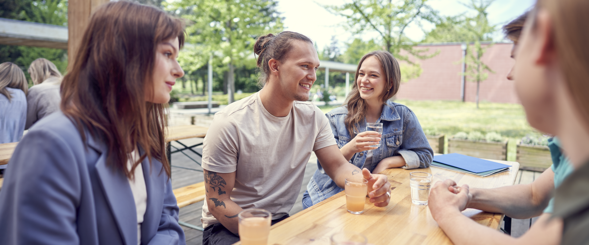 grupa studentów siedzi przy stole w stołówce, pije napoje i rozmawia