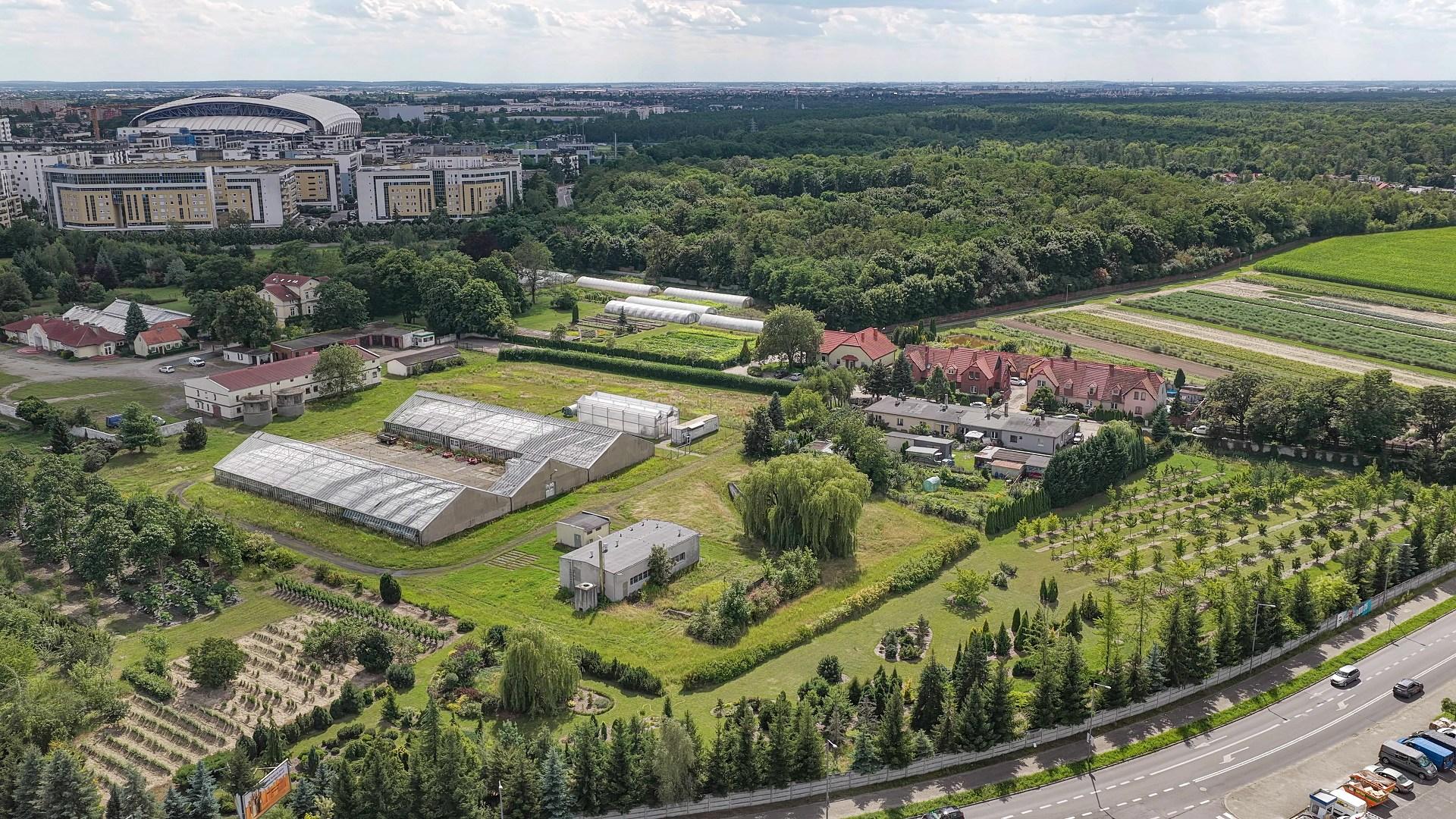 Widok z lotu ptaka na dużą zieloną łąkę z dużym stadionem w tle