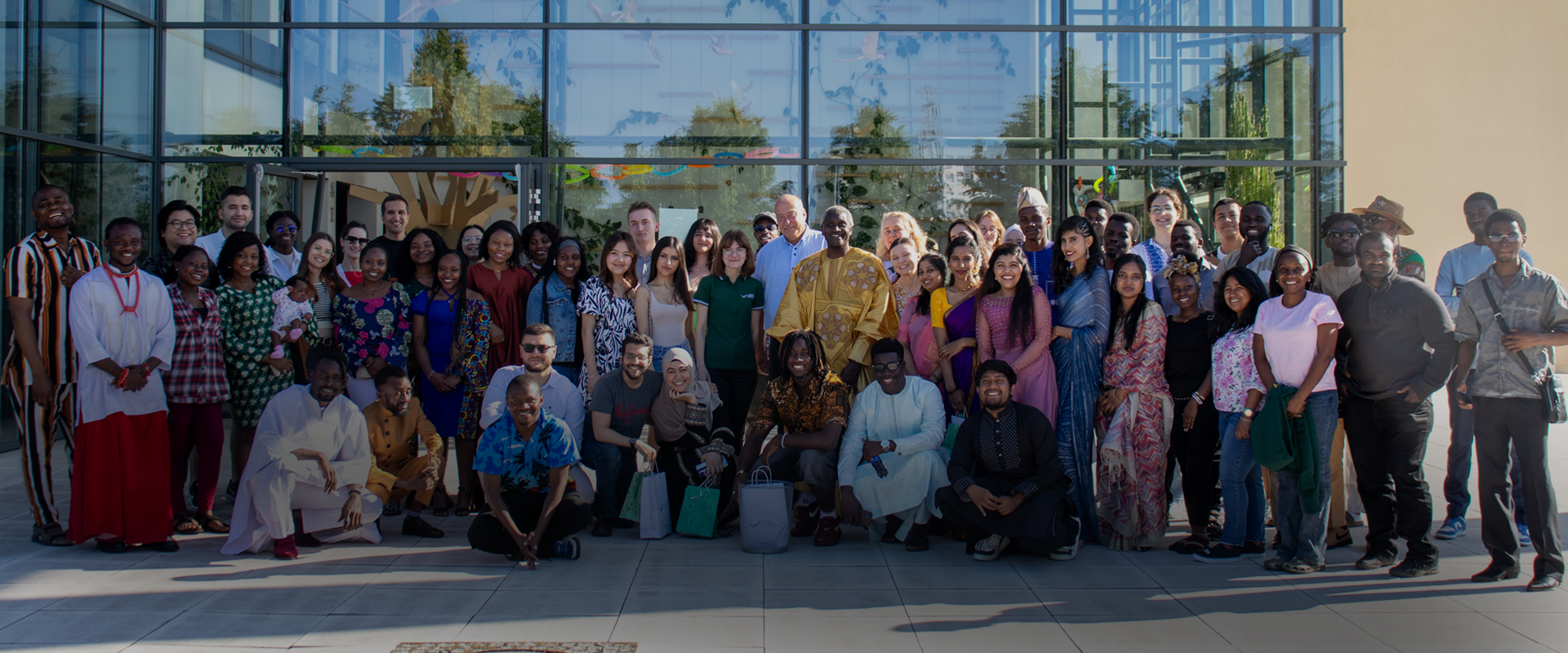 A gGroup of people smiling and posing for a photo in front of a building.