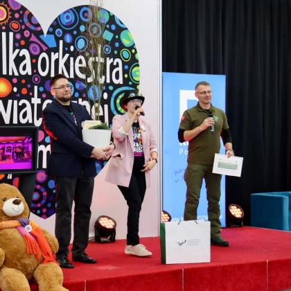 trzy osoby na scenie podczas Finału Wielkiej Orkiestry Świątecznej Pomocy