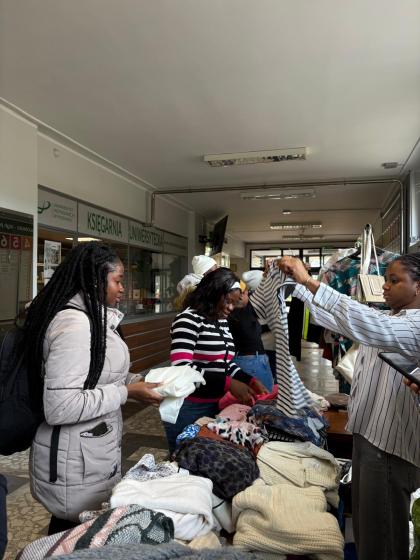 Grupa osób na korytarzu przegląda ubrania