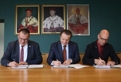 Trzy osoby podczas podpisywania porozumienia