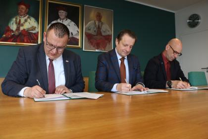 Trzy osoby podczas podpisywania porozumienia