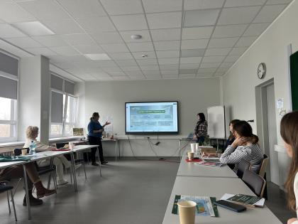 Grupa osób w sali patrzy na ekran