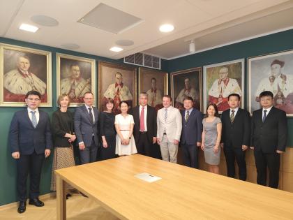 Grupa ludzi z różnych krajów pozująca do na tle portretów byłyvh rektorów UPP