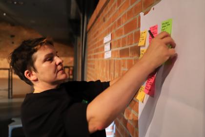 Kobieta przykleja kolejną karteczkę z hasłem na tablicę